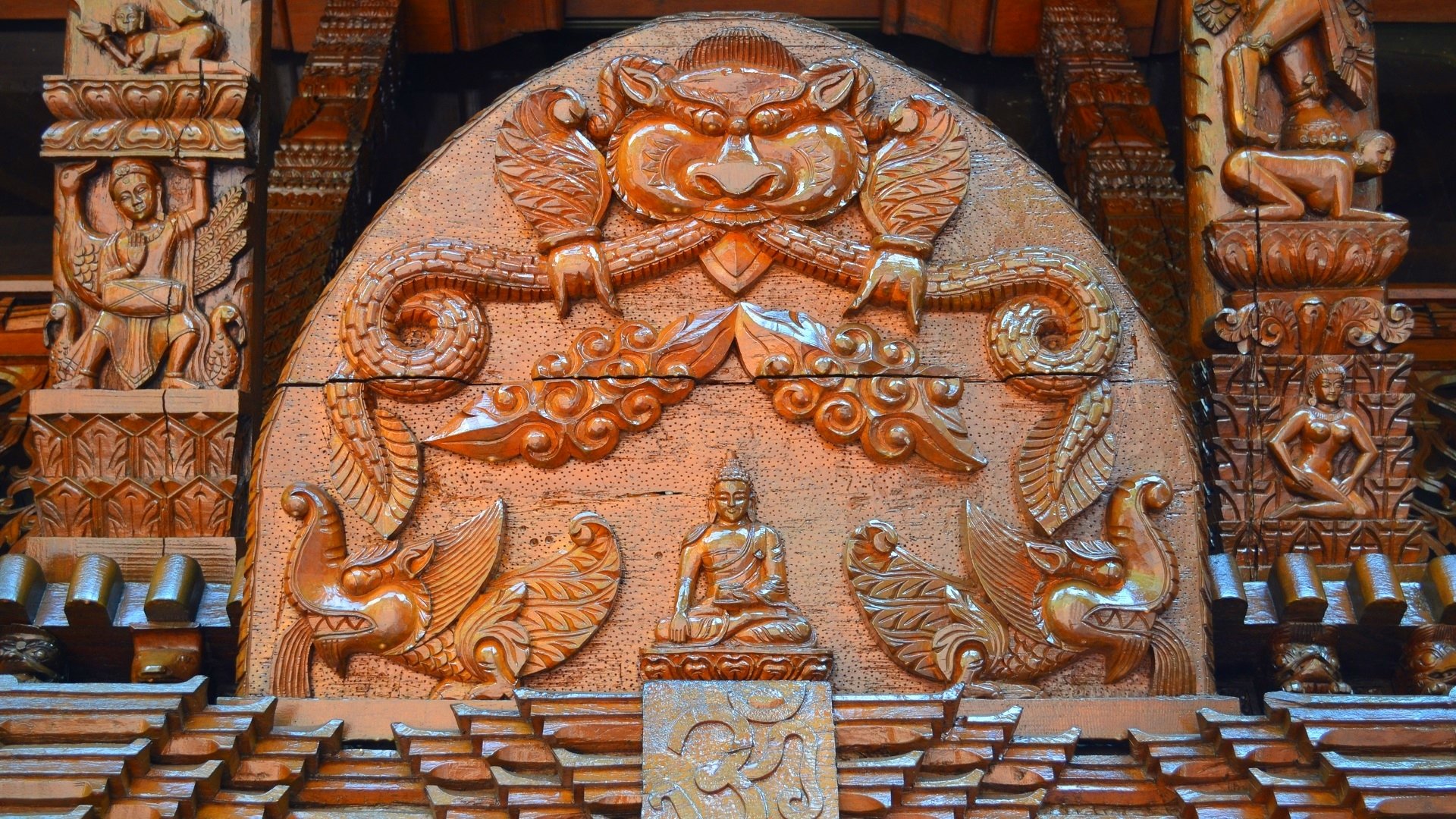 HD photography of a man-made Nepalese pagoda wood carving in Brisbane, close-up of Buddha figure and ornate guardian motifs — PC desktop wallpaper/background.