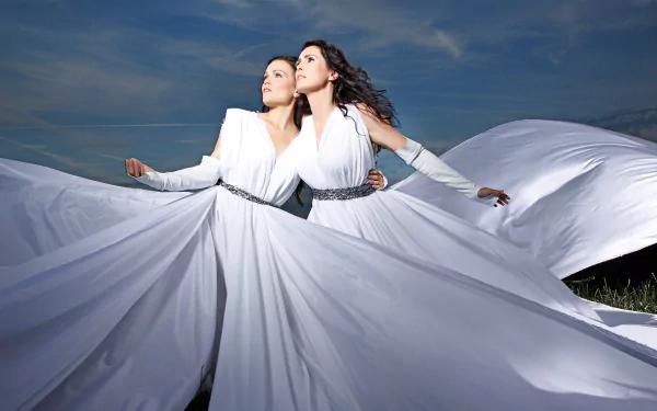 HD PC wallpaper: two women in flowing white gowns beneath a stormy sky, evoking Within Temptation's dramatic, music-themed aesthetic.