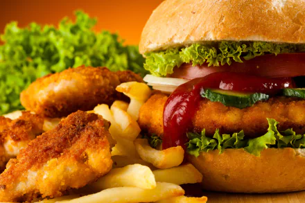 A close-up 4K Ultra HD wallpaper of a juicy hamburger with lettuce, tomato, and ketchup, accompanied by crispy chicken nuggets and golden french fries.