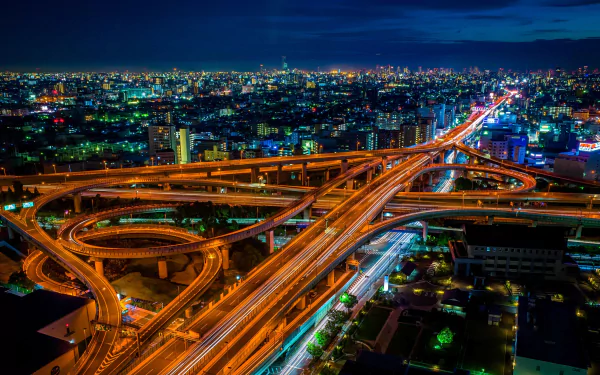 A stunning night view of Osaka's freeway network, showcasing vibrant lights and intricate man-made structures in a 4K Ultra HD desktop background.