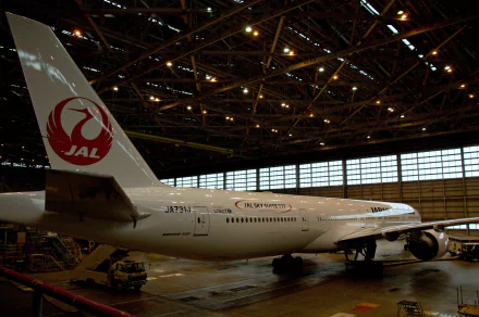 A Boeing 777 aircraft with a Japan Airlines logo is showcased inside a hangar, providing a striking HD desktop wallpaper and background.