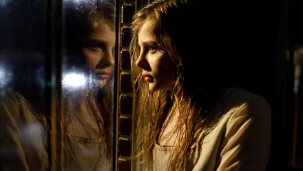 A captivating HD wallpaper featuring Chloë Grace Moretz in a dramatic scene from the movie Let Me In, reflecting an intense moment with her image mirrored beside her.