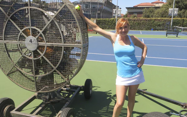 Kari Byron from the TV show Mythbusters poses on a tennis court beside a large fan device in this HD PC desktop wallpaper.