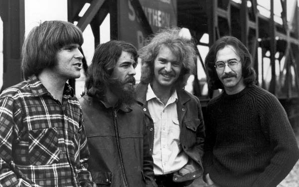 Black-and-white HD desktop wallpaper of the rock band Creedence Clearwater Revival posing outdoors near a bridge or industrial structure.