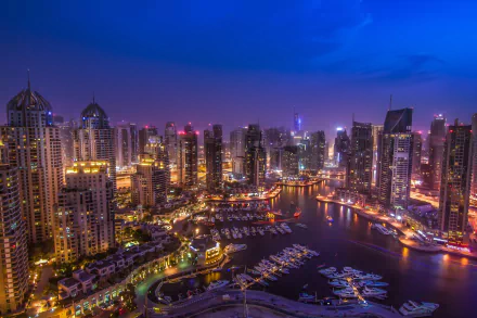 Night view of Dubai Marina with illuminated skyscrapers and yachts, captured in stunning 4K Ultra HD as a man-made urban waterfront in Dubai.