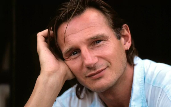 HD desktop wallpaper featuring a contemplative individual resembling a character associated with Liam Neeson, with a hand on their head.
