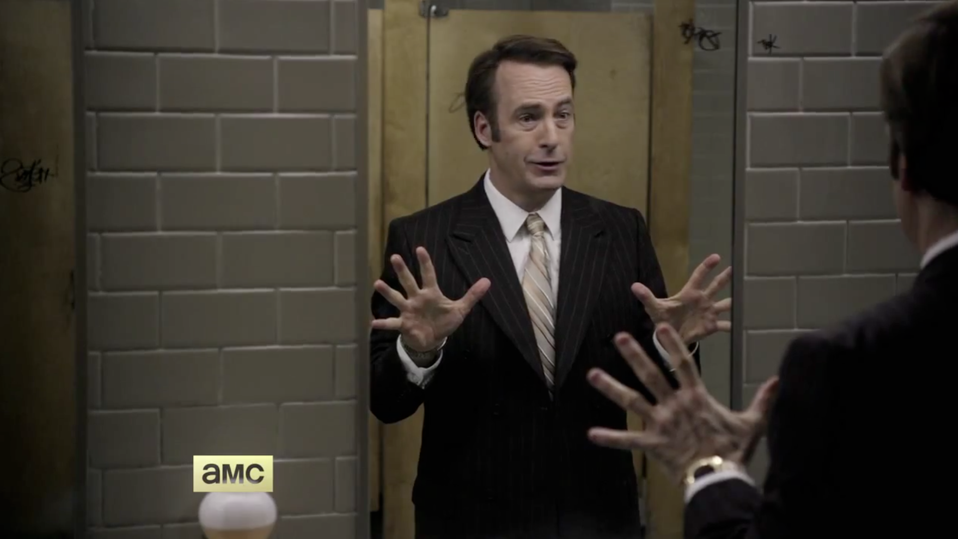 HD desktop wallpaper of Bob Odenkirk as Jimmy McGill in Better Call Saul, standing and gesturing in a bathroom with AMC logo visible.