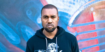 HD desktop wallpaper featuring a person in a black hoodie standing before a graffiti wall, exuding a confident demeanor.