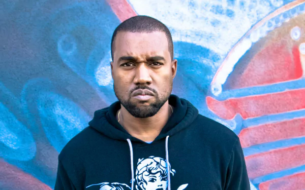 HD desktop wallpaper featuring a person in a black hoodie standing before a graffiti wall, exuding a confident demeanor.
