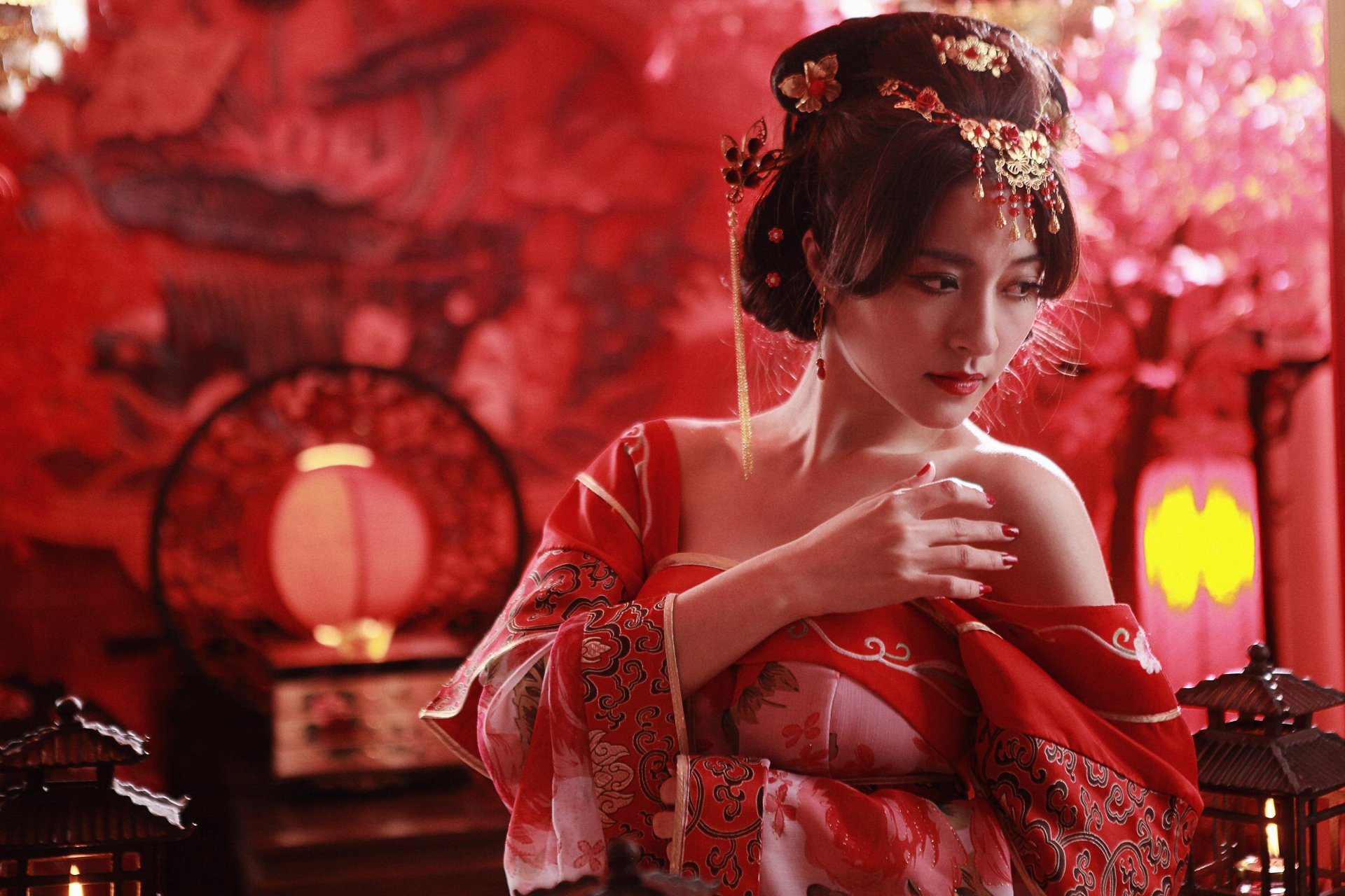 A woman in traditional Taiwanese national dress poses gracefully, adorned with a beautiful hairdo and surrounded by a warm, red ambiance with candles and lanterns.