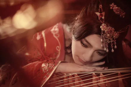 An Asian woman in traditional national dress rests her head near a stringed instrument, embodying serene beauty in this 4K Ultra HD hair-dress themed wallpaper.