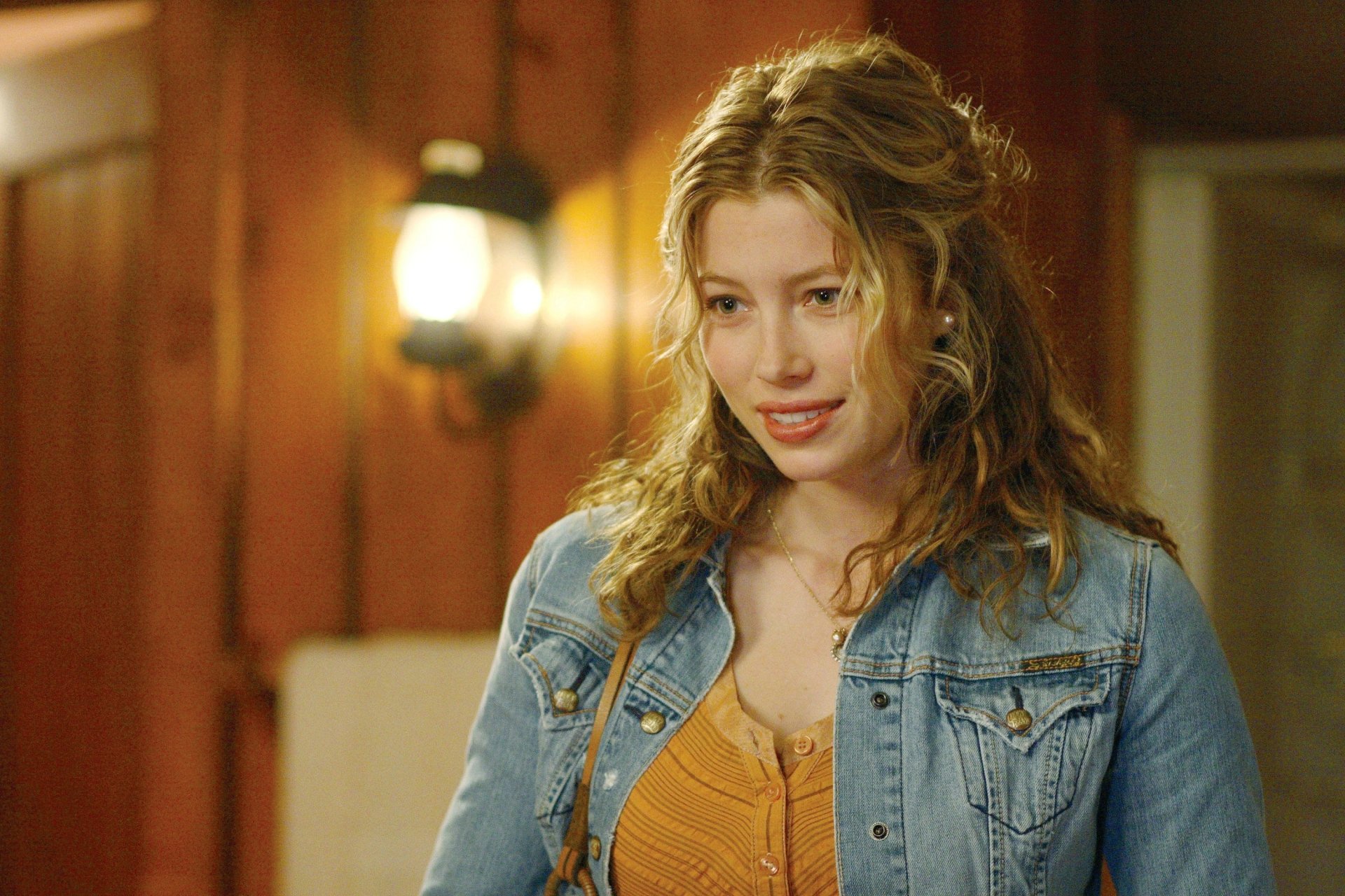 HD PC desktop wallpaper featuring celebrity Jessica Biel smiling indoors with warm lighting and casual attire.