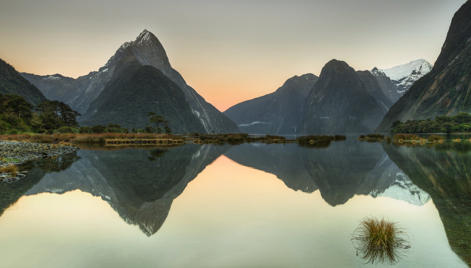 Mitre Peak in Milford Sound, Aotearoa/New Zealand — Southern Alps and jagged peaks mirrored in a tranquil fjord at sunrise. 5K Ultra HD desktop wallpaper.