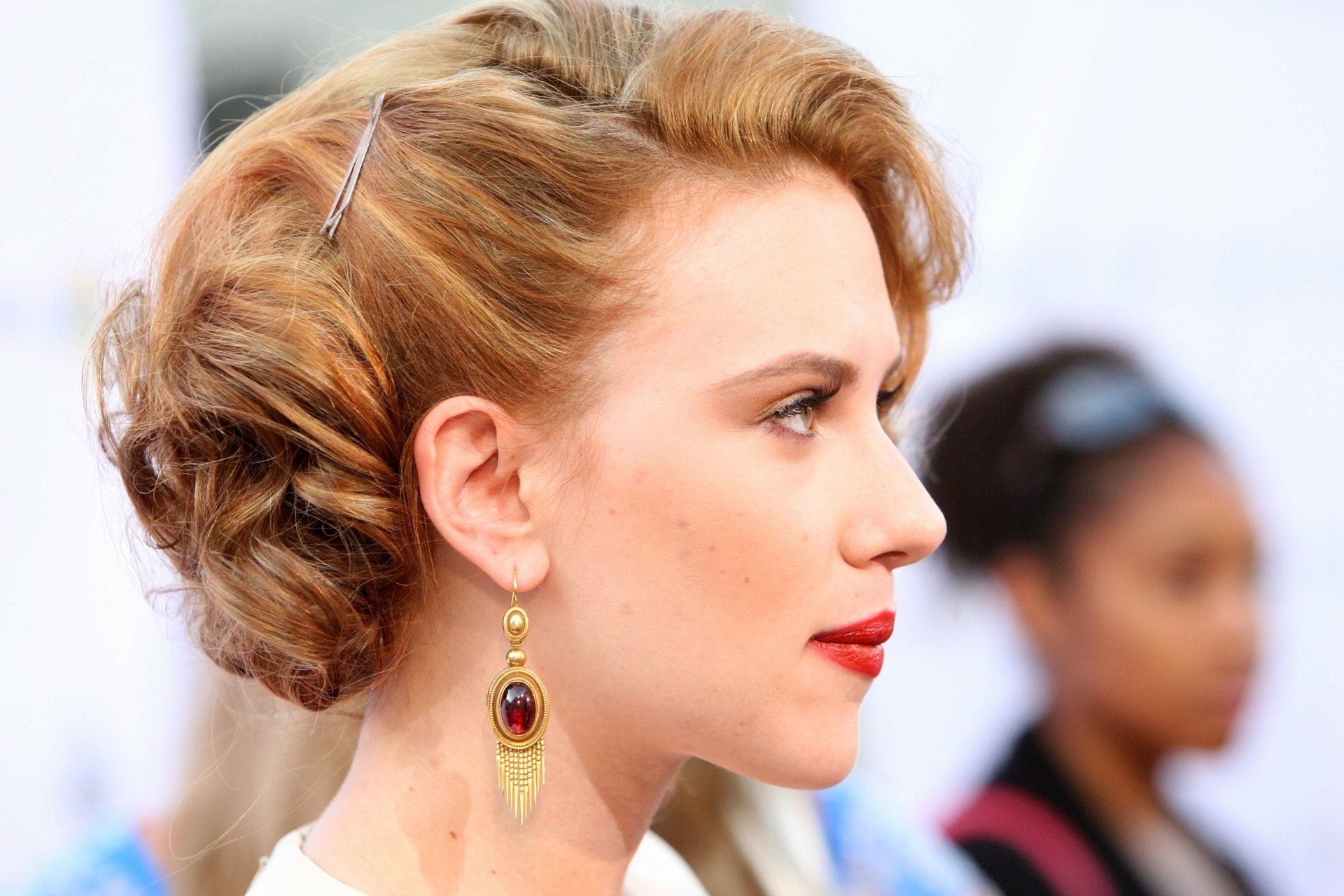 Scarlett Johansson is captured in profile, showcasing her elegant hairstyle and striking red lips, set against a blurred background for a sophisticated HD desktop wallpaper.
