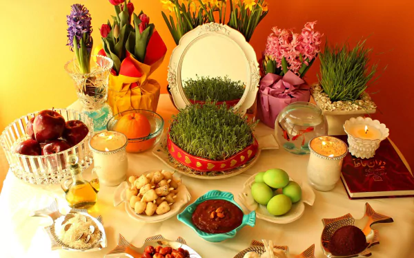 HD PC desktop wallpaper showcasing a vibrant Nowruz holiday table with traditional Haft-Seen items, including sabzeh, candles, fruits, and decorative flowers.