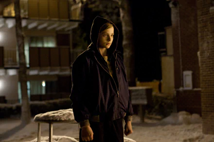 Chloë Grace Moretz stands in a snowy outdoor scene from the movie Let Me In, embodying a mysterious and captivating presence in this HD desktop wallpaper.