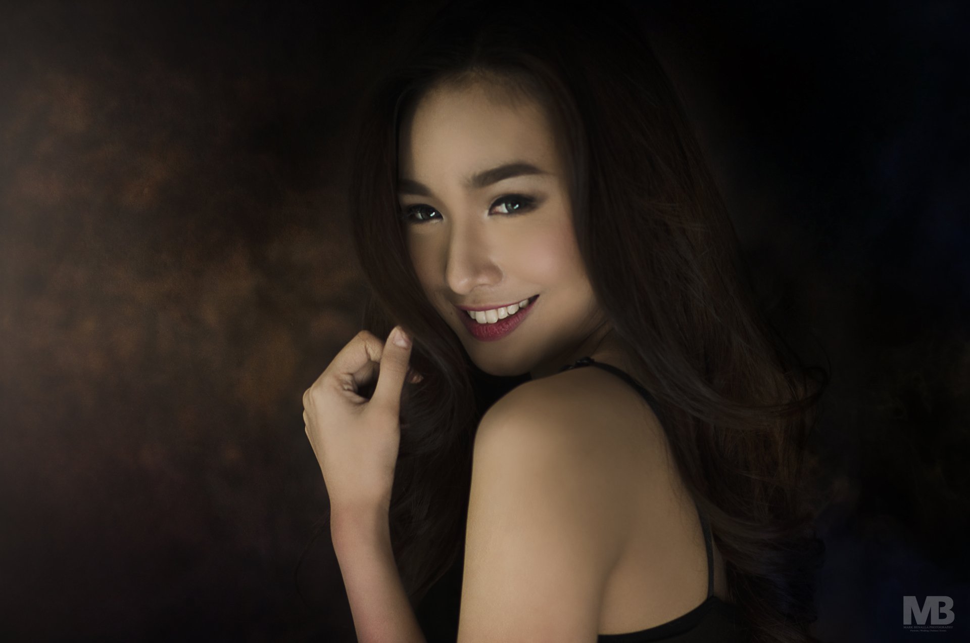 A smiling Asian woman poses gracefully, showcasing her beauty against a soft, dark background. This 4K Ultra HD image serves as an elegant desktop wallpaper.
