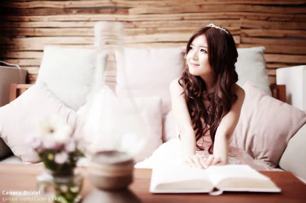 HD desktop wallpaper featuring an Asian woman, tagged as a Vietnamese bride and model, sitting with a book and smiling. The setting exudes a relaxed and happy mood.