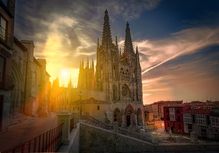 Sunrise casts golden light on the Gothic spires of Burgos Cathedral in Spain, highlighting its intricate religious architecture against a vibrant dawn sky.