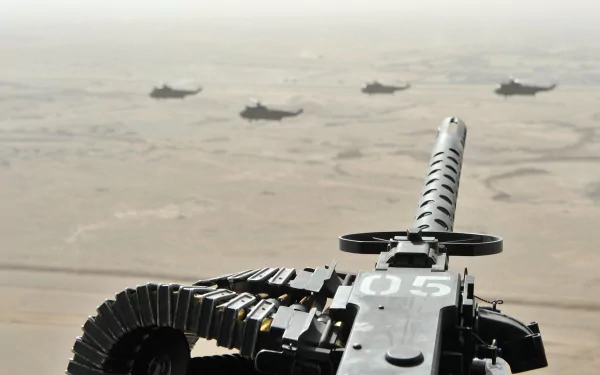 A close-up view of a machine gun with a desert landscape and military vehicles in the background, creating a striking HD desktop wallpaper.