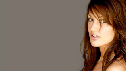 Minka Kelly poses with a subtle expression, showcasing her long hair and natural beauty against a soft gray background. This HD wallpaper captures her elegance perfectly.