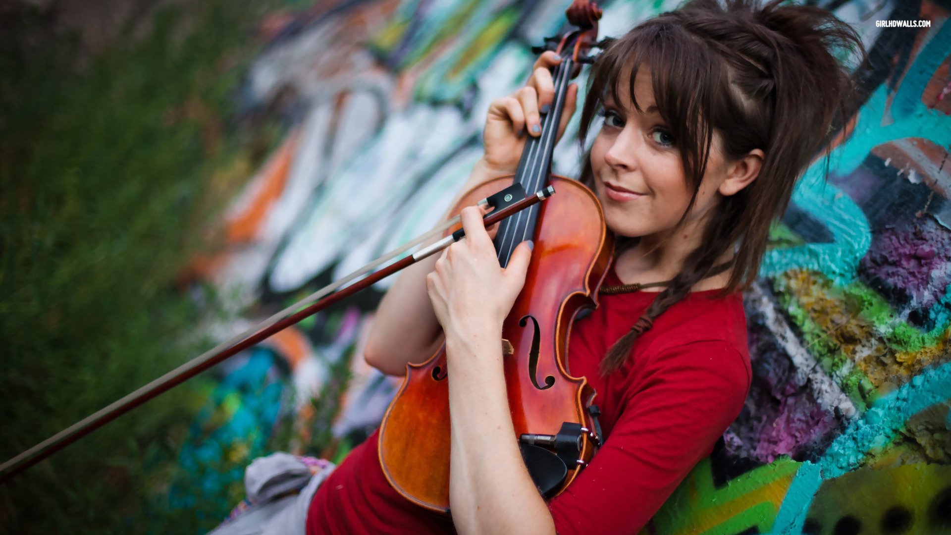 HD desktop wallpaper featuring musician Lindsey Stirling playing the violin against a colorful graffiti background.