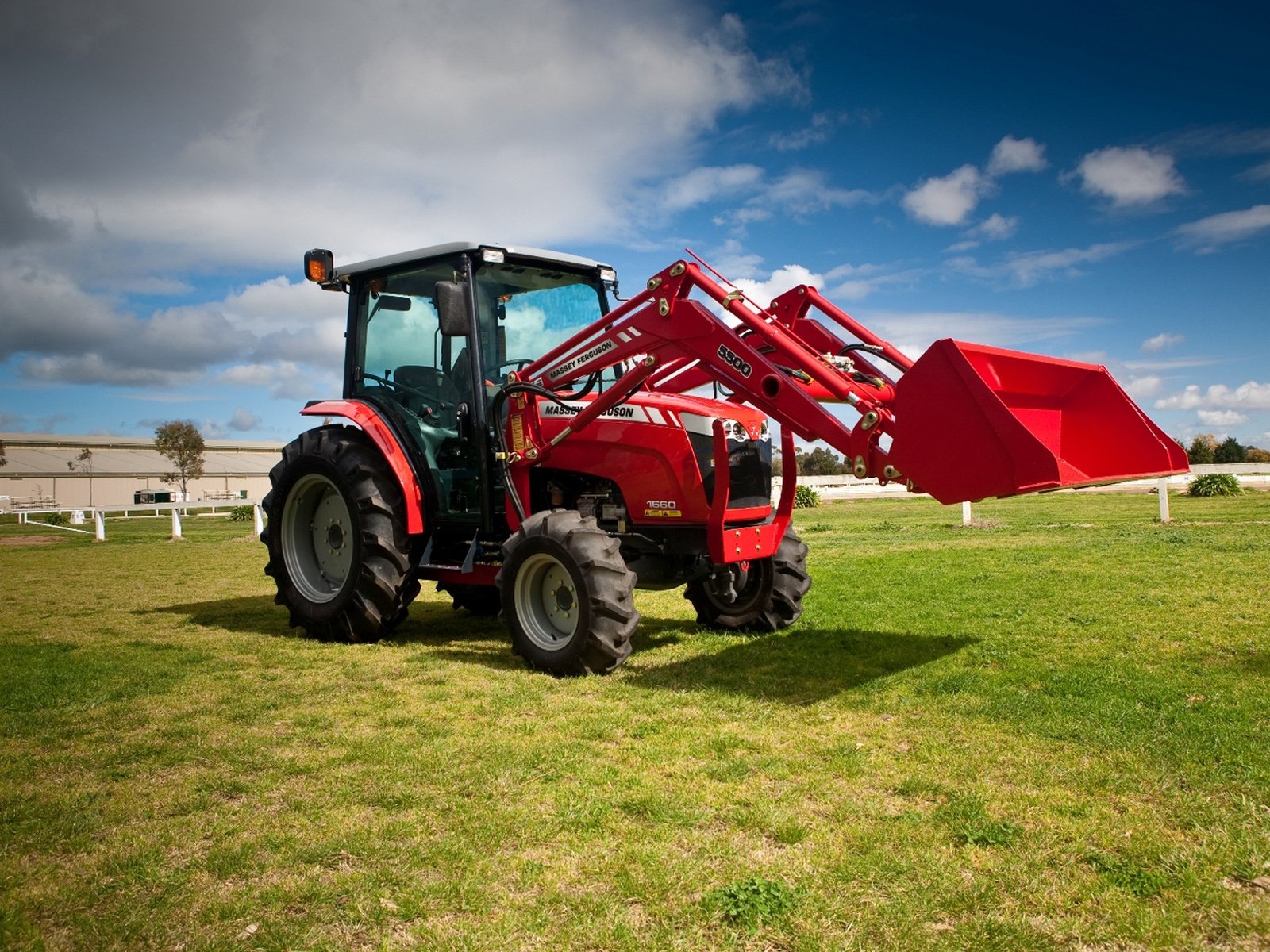 A vibrant red Massey Ferguson tractor is parked on green grass, showcasing its front loader against a bright blue sky, making this an engaging HD desktop wallpaper.