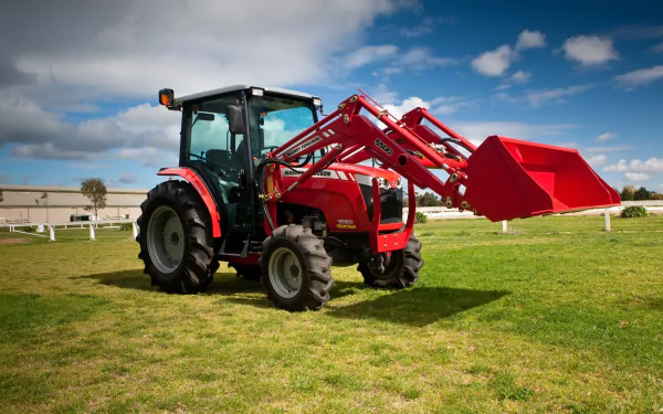 A vibrant red Massey Ferguson tractor is parked on green grass, showcasing its front loader against a bright blue sky, making this an engaging HD desktop wallpaper.