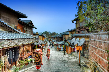 A serene street in Higashiyama, Kyoto, featuring a maiko and a geisha walking past traditional wooden buildings, showcasing the charm of Japan’s cultural heritage.