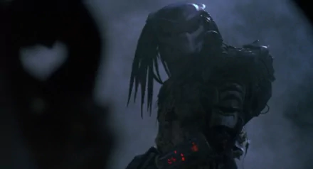 A dramatic HD wallpaper featuring the iconic Predator from the movie, showcasing its menacing presence in a shadowy, atmospheric setting.