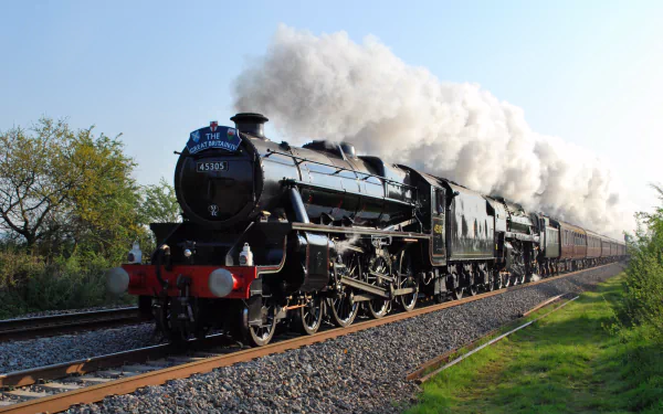 A vintage steam train chugs along tracks under a clear sky, captured in stunning detail as a 4K Ultra HD PC desktop wallpaper and background.