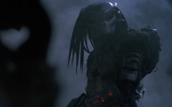 A dramatic HD wallpaper featuring the iconic Predator from the movie, showcasing its menacing presence in a shadowy, atmospheric setting.