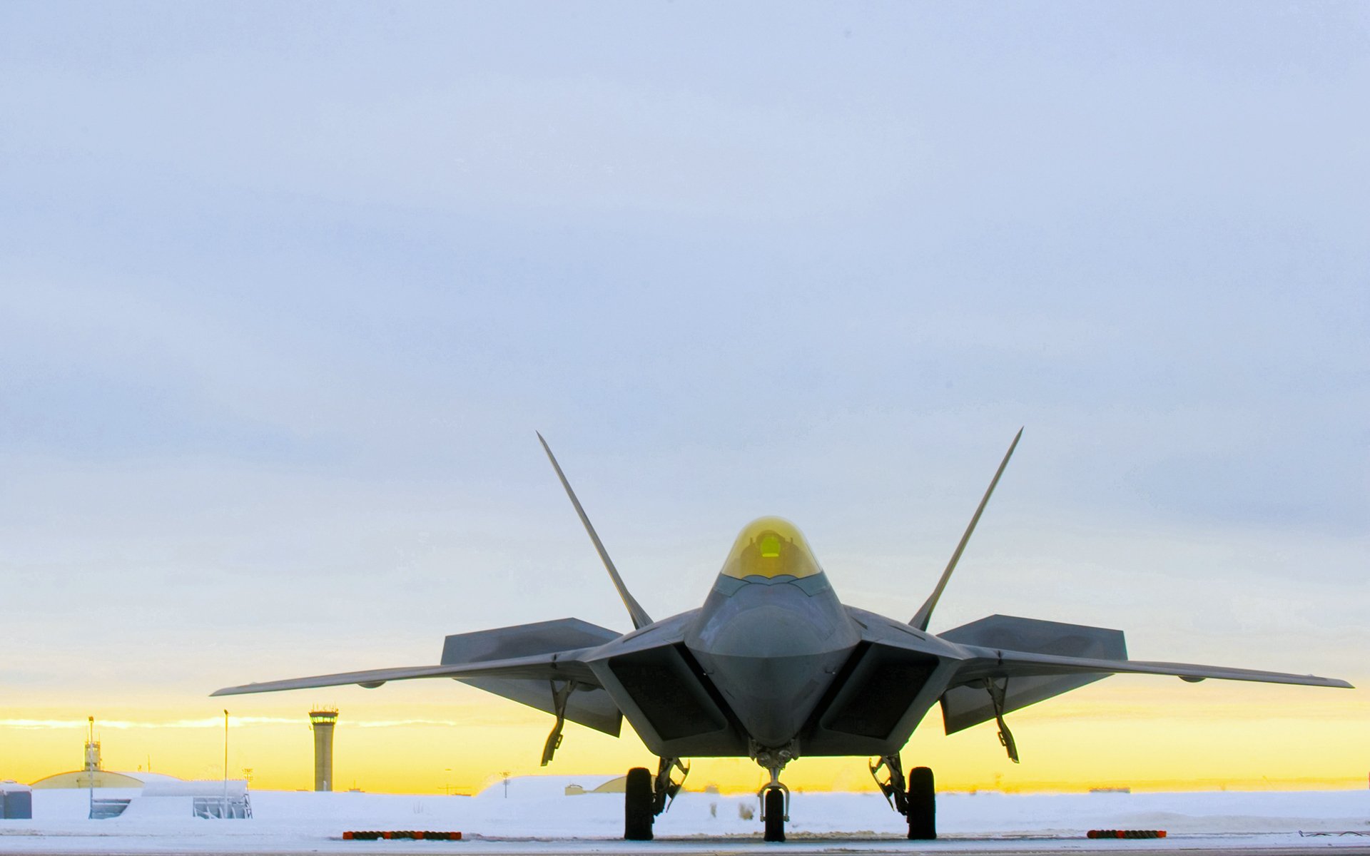 Lockheed Martin F-22 Raptor stealth military aircraft on runway at sunset, captured in HD for a striking desktop wallpaper background.