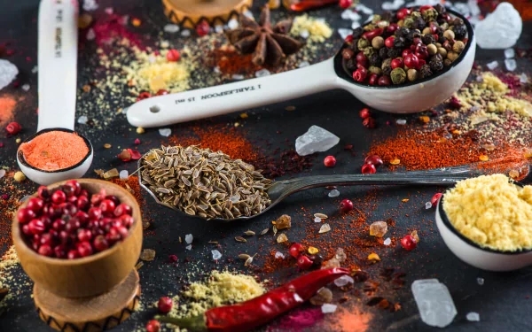 5K Ultra HD PC desktop wallpaper of colorful peppers, mixed peppercorns, herbs and spices—whole and ground, with rock salt scattered on a dark background.