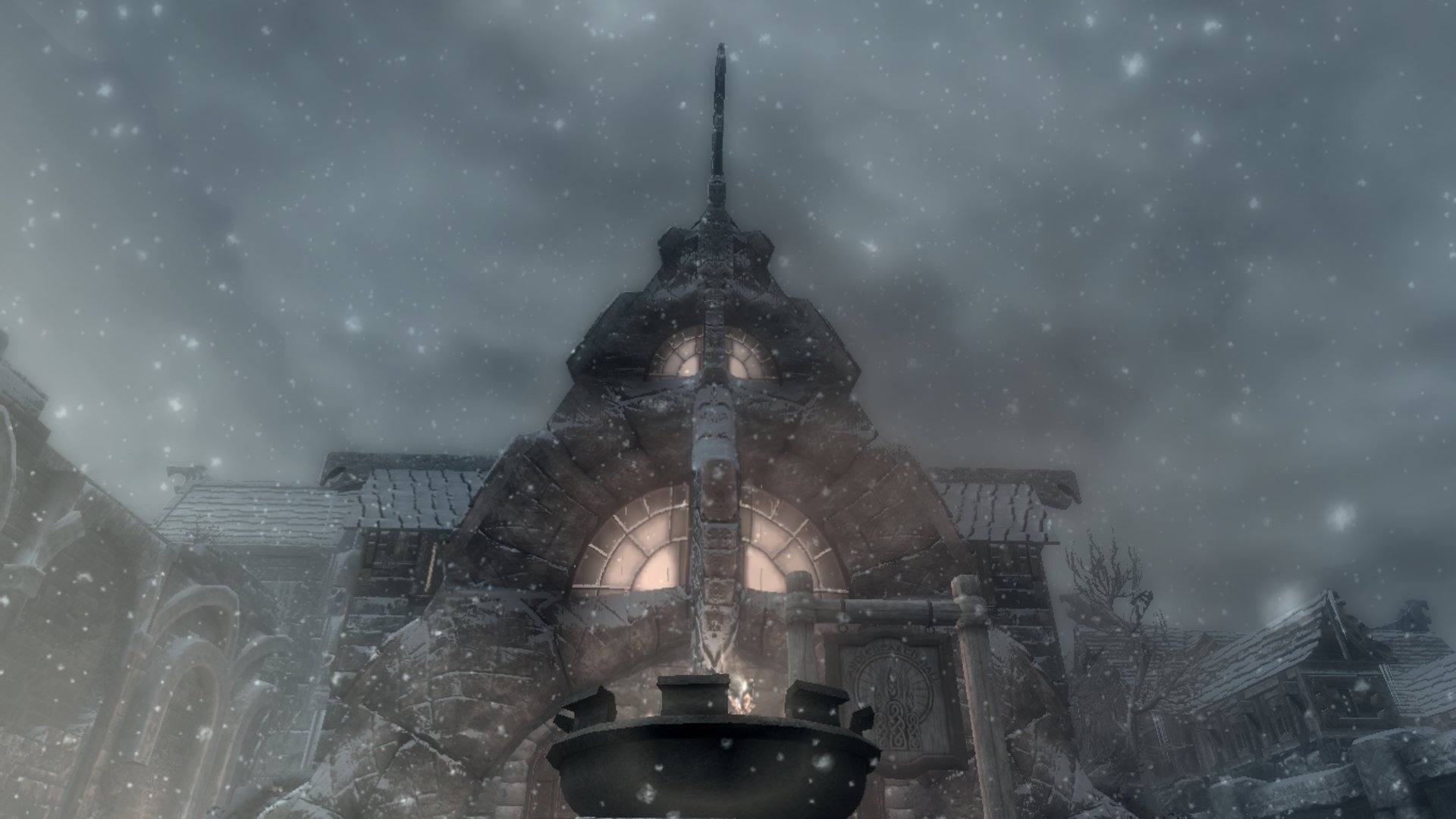 HD PC desktop wallpaper featuring a snowy, dramatic scene from the video game The Elder Scrolls V: Skyrim, showcasing a medieval stone building under heavy snowfall.