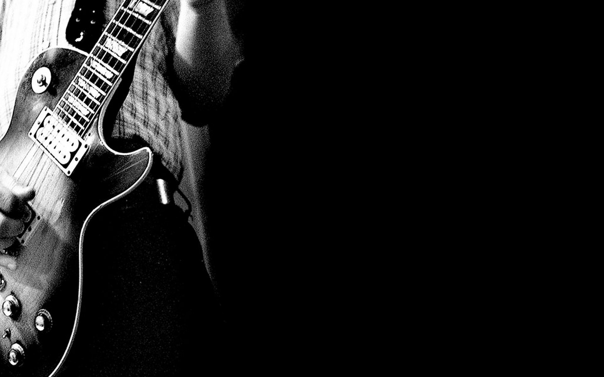 Black and white HD desktop wallpaper featuring a close-up of a person playing an electric guitar, highlighting the instrument and musician’s hands against a dark background.