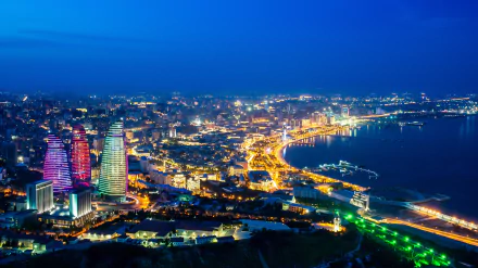 Stunning panoramic view of Baku at night, featuring the iconic Flame Towers illuminated against the city skyline, showcasing Azerbaijan's vibrant urban landscape. Perfect HD desktop wallpaper.