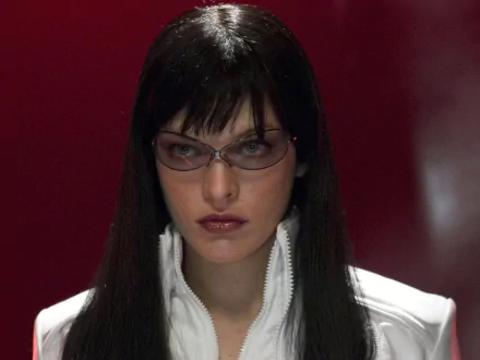 HD PC desktop wallpaper featuring a close-up of a woman with dark hair and sunglasses from the movie Ultraviolet against a deep red background.