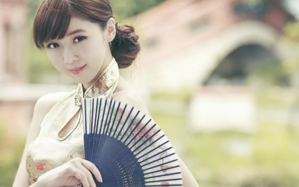 HD desktop wallpaper of Taiwanese model Chén Qiáoqiáo smiling softly, holding a fan with a blurred bokeh background.