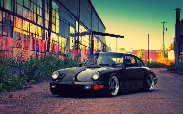 Black Porsche 993 parked on an industrial street at sunset, captured in high definition for a striking PC desktop wallpaper.