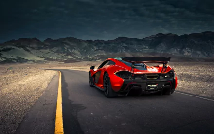 HD desktop wallpaper featuring a red McLaren P1 against a dramatic mountain landscape, highlighting the vehicle's sleek design on a deserted road.