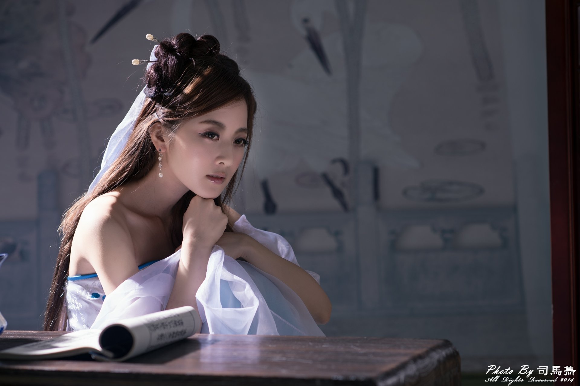 Elegant woman in traditional hair-dress with hairpin and dangling earrings, seated at a desk — 4K Ultra HD desktop wallpaper.