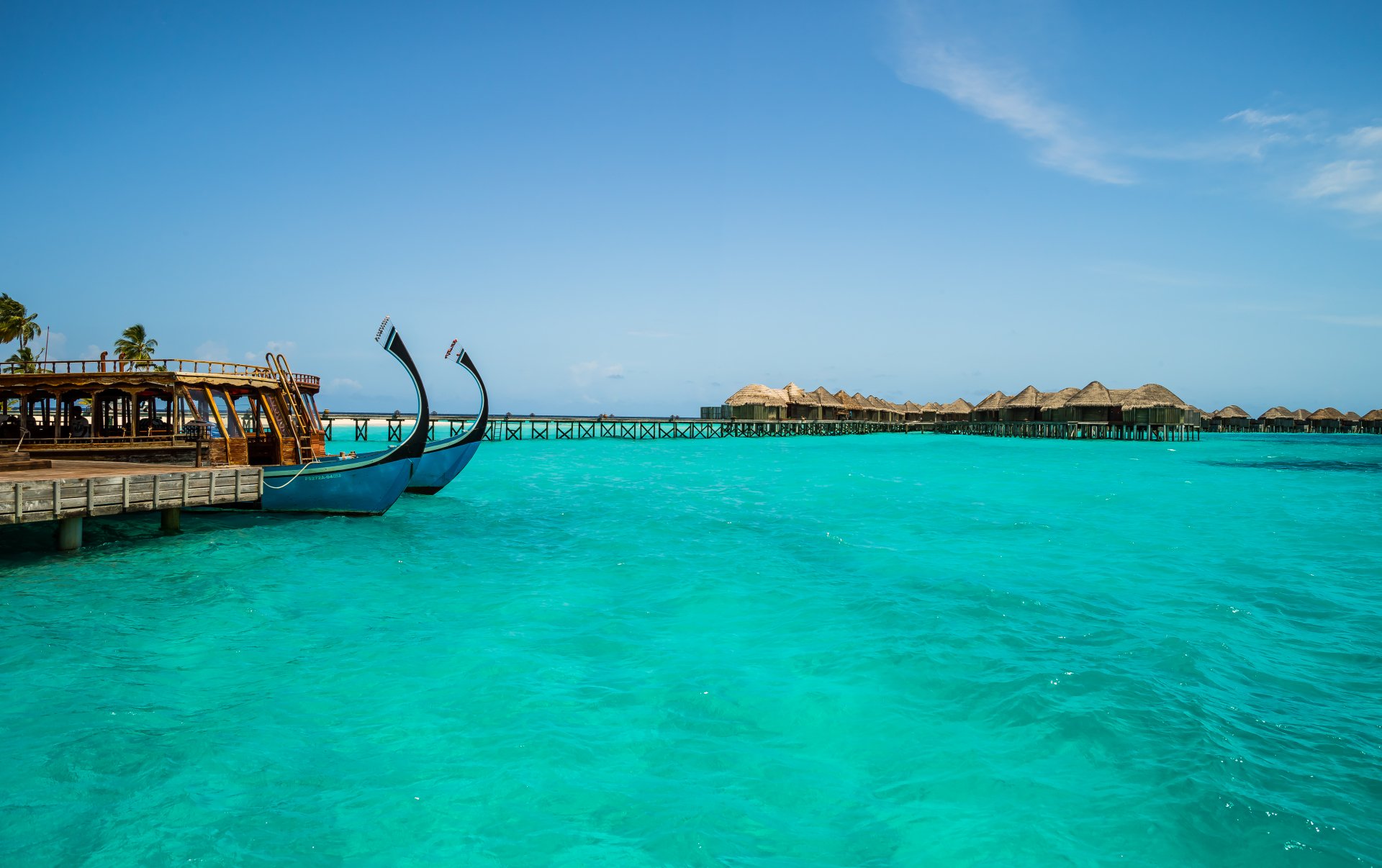 Vibrant turquoise lagoon with boats at the Constance Halaveli Resort pier, surrounded by tropical beauty in the Maldives, captured in stunning 4K Ultra HD.