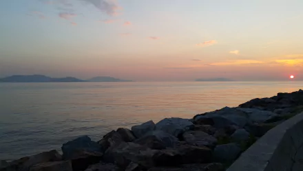 5K Ultra HD photography sunset: calm coastal seascape with pastel sky, distant mountains and rocky shoreline, PC desktop wallpaper and background.