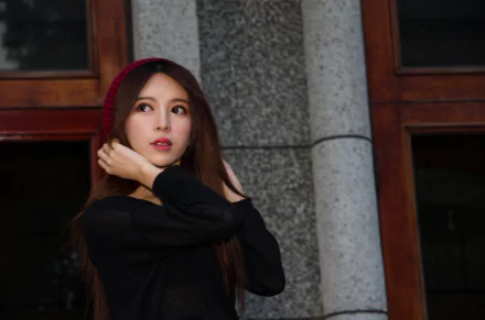 Female model posing by a stone column and wooden window, wearing a red knit hat and black top — 4K Ultra HD PC desktop wallpaper.