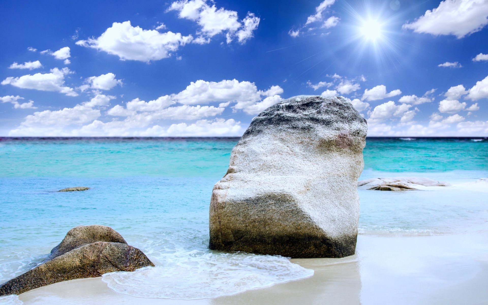 4K Ultra HD PC desktop wallpaper: sunny summer beach landscape and nature with sand, sea and ocean-tinted turquoise water, scattered rocks and clear sky.