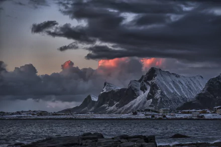 A stunning Arctic scene from the Lofoten Islands in Norway, featuring dramatic clouds above snow-capped mountains, a serene village, and the shimmering sea at sunset.