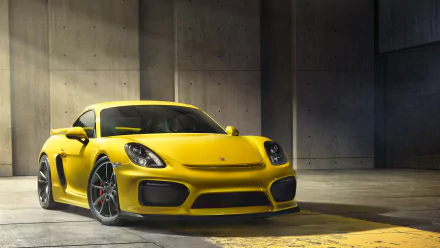 Yellow Porsche Cayman GT4 sports car parked in a modern concrete garage, captured in high definition for a vibrant PC desktop wallpaper background.