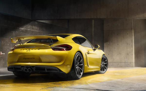 Yellow Porsche Cayman GT4 sports car parked in a modern concrete garage, showcased as an HD PC desktop wallpaper and background.