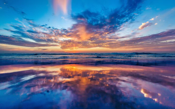 A stunning HD wallpaper showcasing a vibrant sunset sky, with colorful clouds reflecting on the tranquil ocean surface, capturing the beauty of nature.